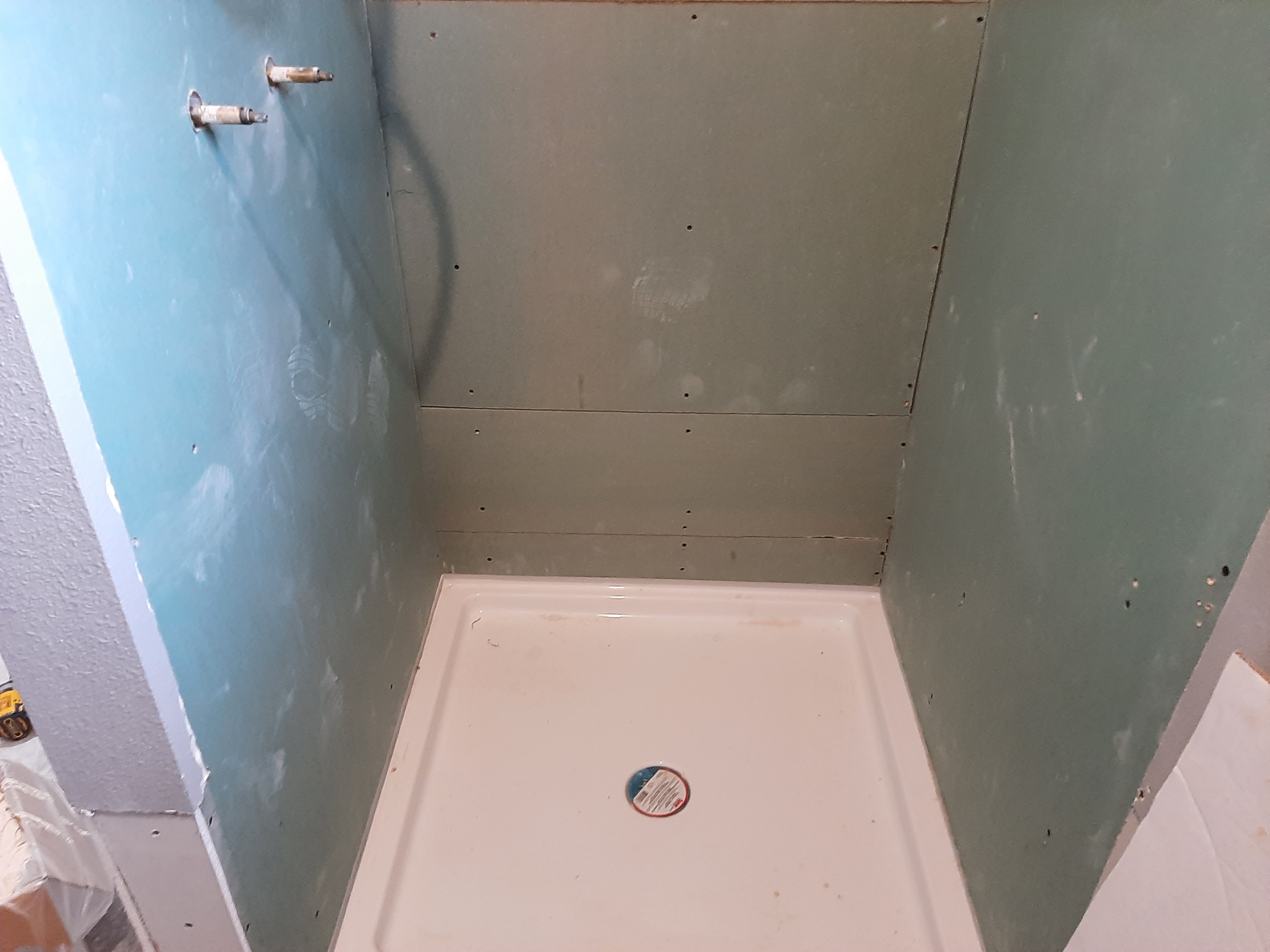 Bathroom remodel in progress with drywall and tools