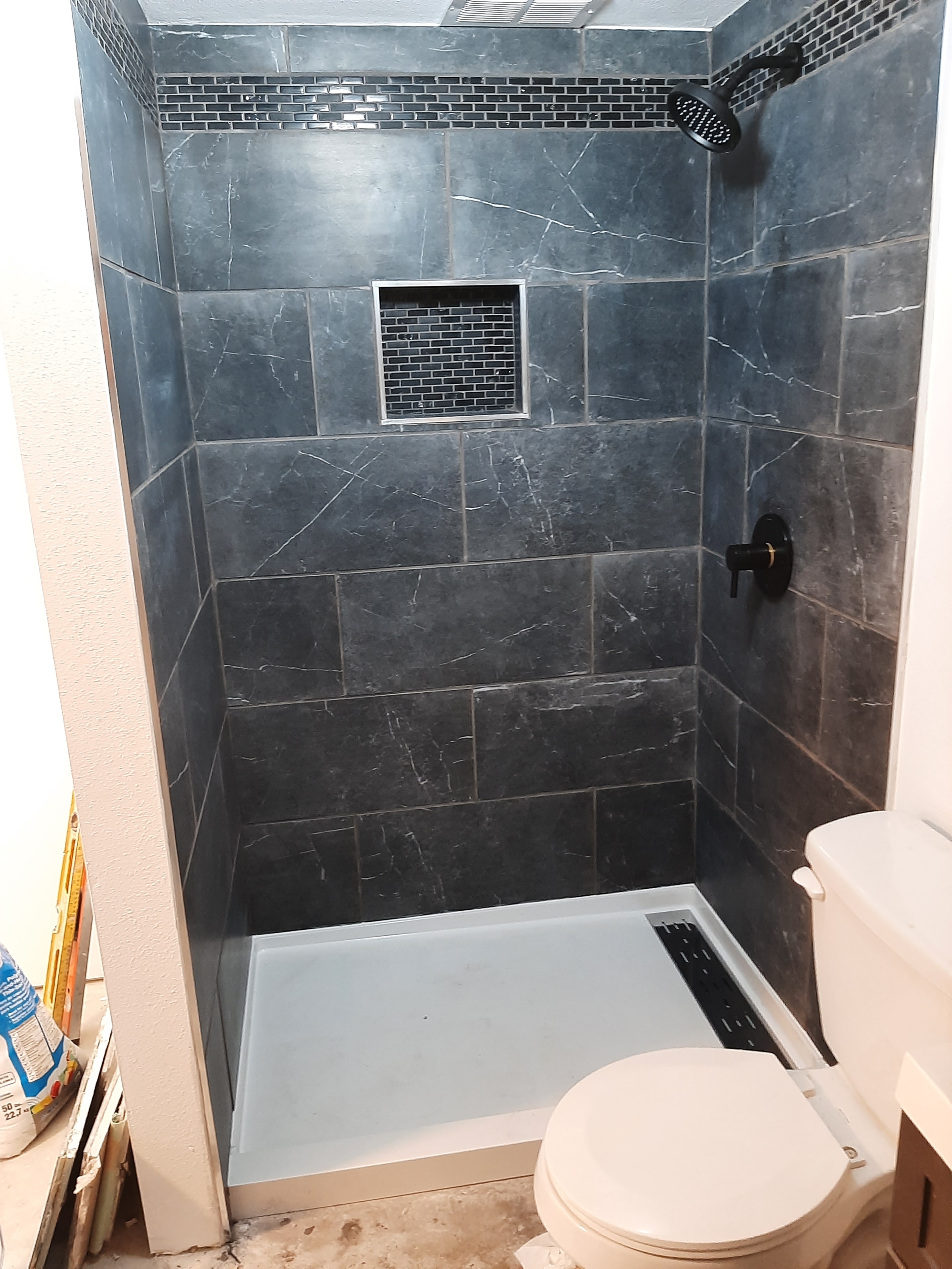 Completed dark marble tile shower with matte black fixtures