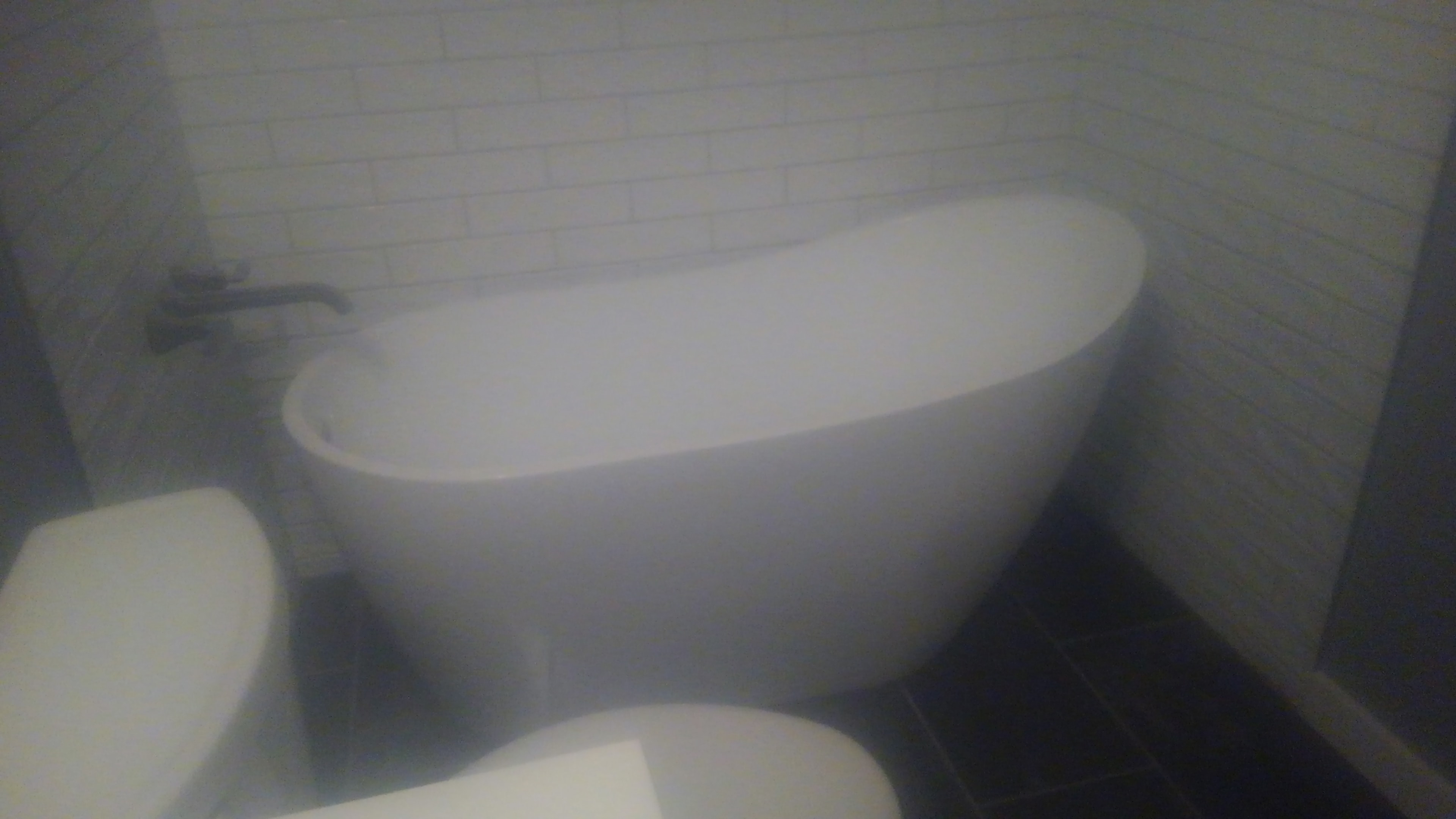 Bathroom with soaking tub and dark tile floor