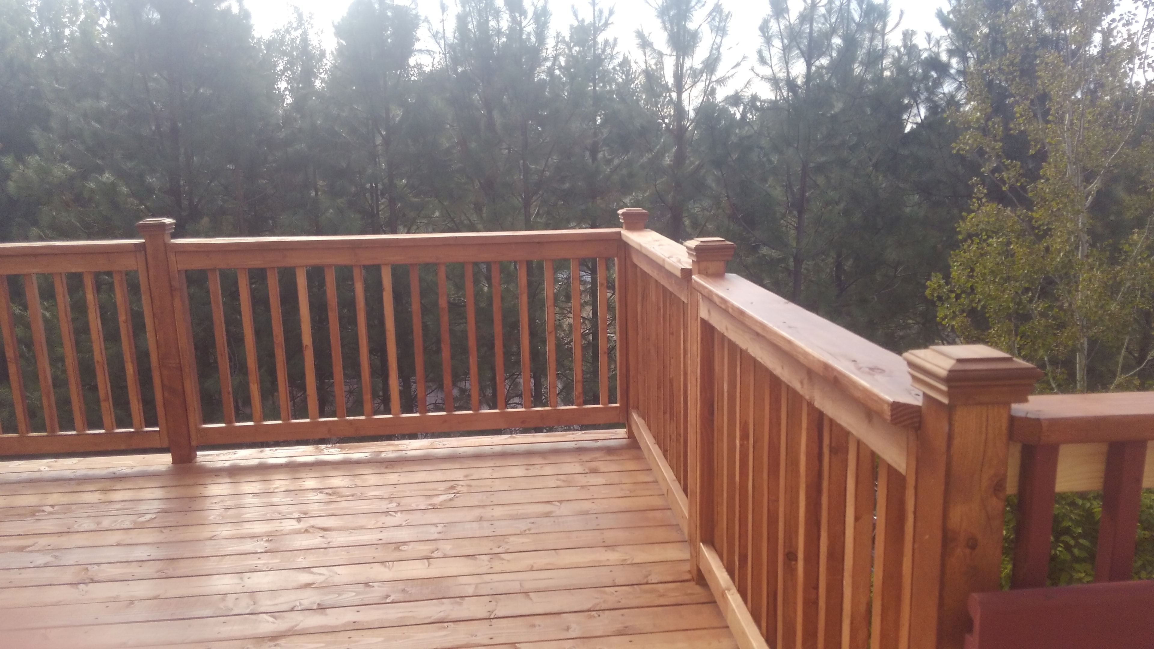 Cedar deck with decorative post caps and pine forest backdrop